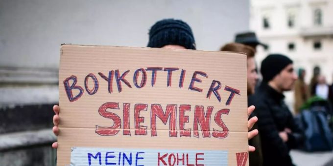 Eine Demonstrationsteilnehmerin hält während einer Protestaktion von Fridays for Future vor der Siemens Zentrale in München ein Schild in die Höhe. Foto: Matthias Balk/dpa Eine Demonstrationsteilnehmerin hält während einer Protestaktion von Fridays for Future vor der Siemens Zentrale in München ein Schild in die Höhe. Foto: Matthias Balk/dpa