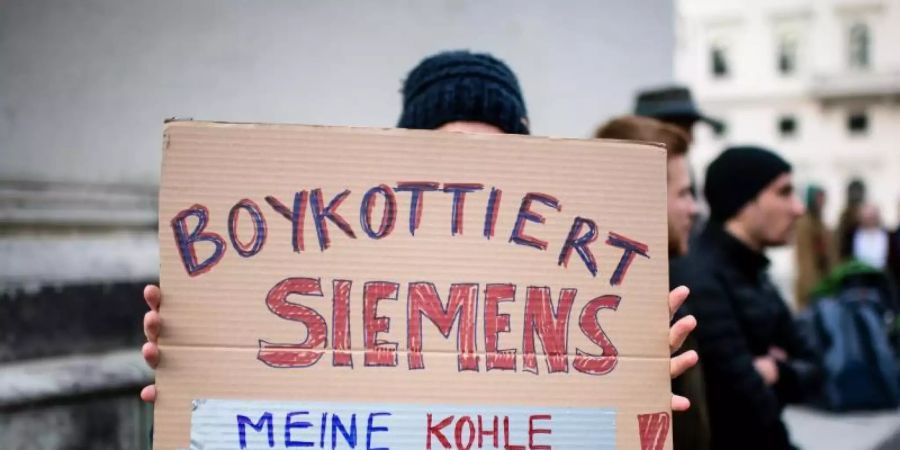 Eine Demonstrationsteilnehmerin hält während einer Protestaktion von Fridays for Future vor der Siemens Zentrale in München ein Schild in die Höhe. Foto: Matthias Balk/dpa