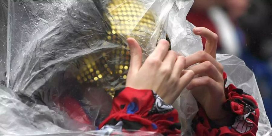 Eine Frau schützt sich mit einem Poncho vor dem Regen beim Rosenmontagszug in Köln (Archiv). Auch in diesem Jahr soll es in den Karnevalshochburgen nass werden. Foto: Federico Gambarini/dpa