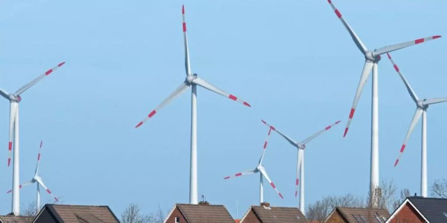 Windräder eines Windparks hinter einer Wohnsiedlung. Foto: Ingo Wagner/dpa