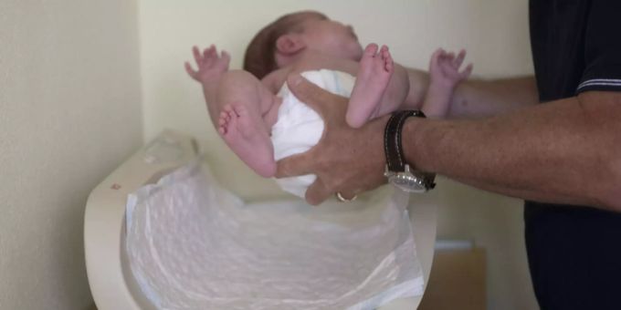 Eine Kinderärztin legt einen Säugling auf eine Waage. Baby