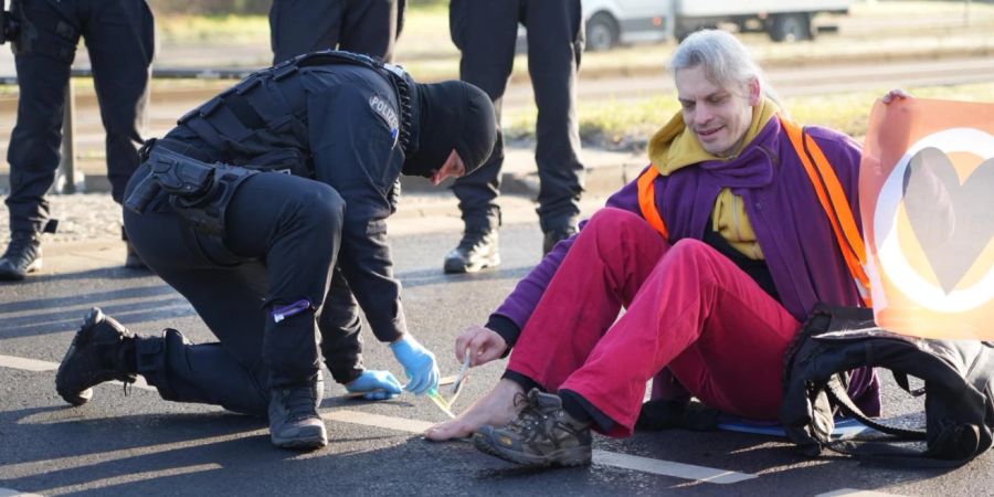 Klima-Kleber Christian Bläul hat sich hier mit seinem Fuss auf die Strasse geklebt.