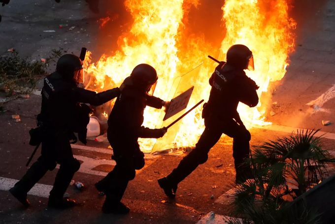 Polizisten laufen an einer brennenden Strassenbarrikade vorbei. Katalanische Separatistenführer verurteilt