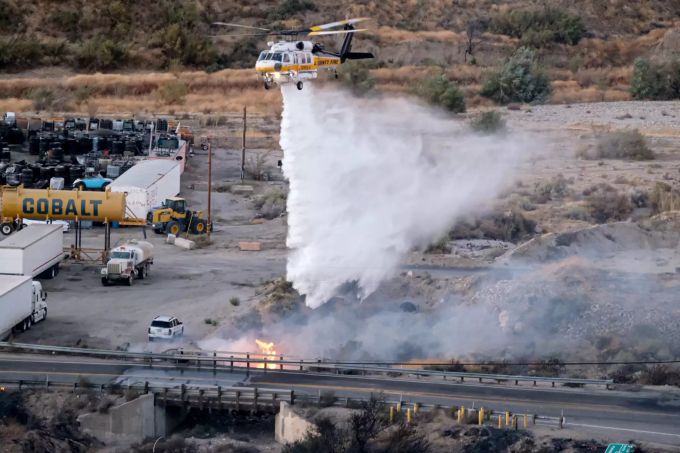 Ein Hubschrauber wirft Löschwasser ab. Gefährliche Waldbrände haben im US-Bundesstaat Kalifornien Zehntausende Menschen in die Flucht getrieben. Um die Gefahr weiterer Brände durch beschädigte Leitungen zu bannen, schalteten Energieversorger mancherorts den Strom ab. Foto: David Crane Waldbrände in Kalifornien