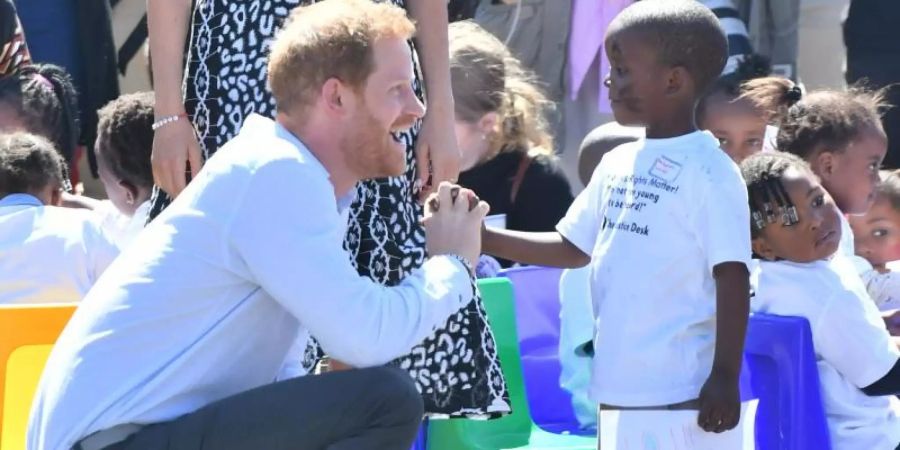 Der britische Prinz Harry mit einem Kind im Nyanga-Township in Kapstadt. Foto: Dominic Lipinski