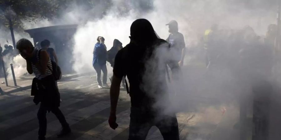 Demonstranten stehen in Paris im Tränengasnebel. Foto: Thibault Camus/AP