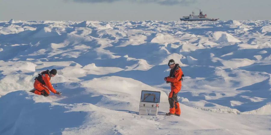 Zwei Forscher sammeln Schnee-Proben 2017 in der Arktis. Im Hintergrund ist die «Polarstern».