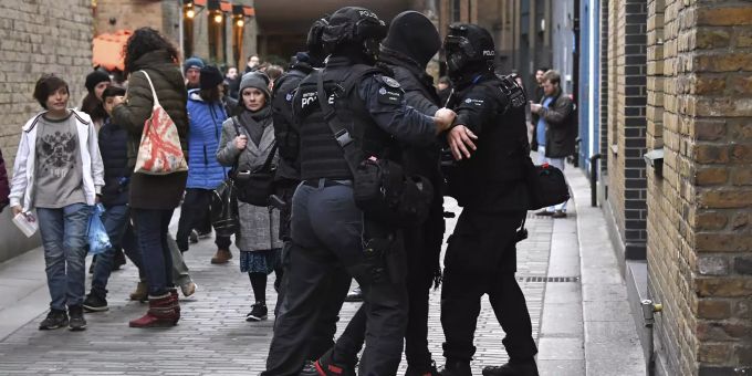 Drei Polizisten untersuchen einen Mann in London. London Messerattacke