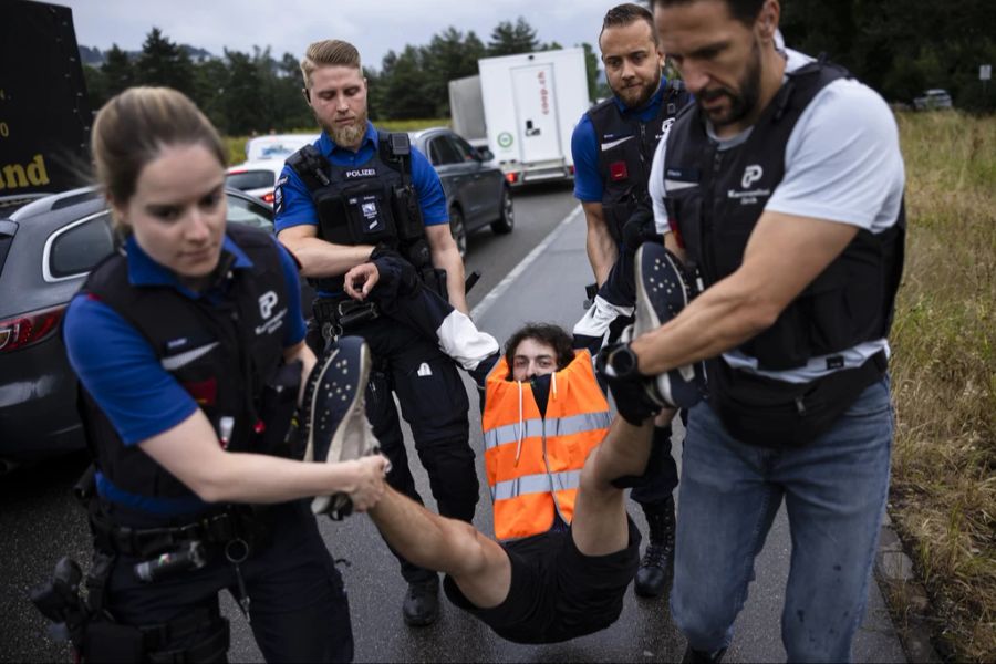 Polizisten müssen Anhänger der Gruppe meist von der Strasse tragen, da sie sich weigern, sie selbständig zu verlassen.