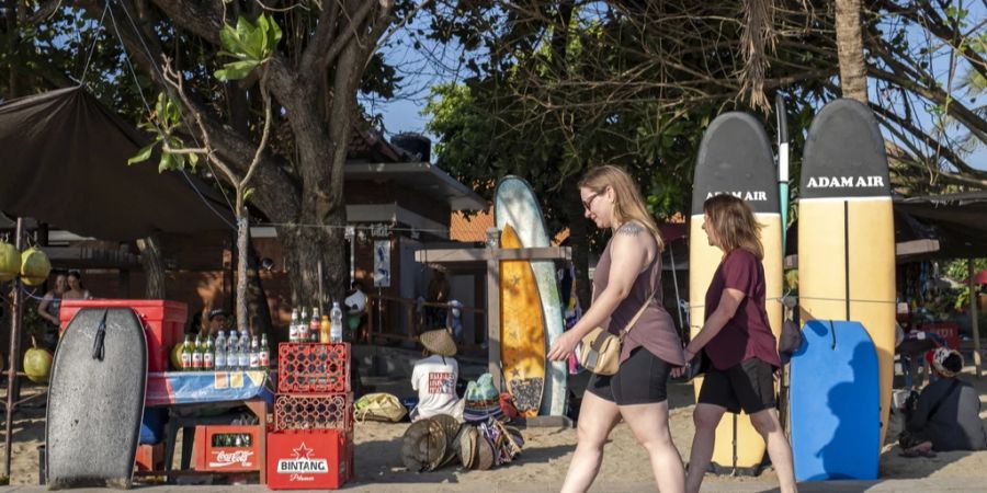 Zwei Touristen laufen in Kuta auf Bali (IDN) am Strand entlang. Sie verhalten sich anständig – und sind somit die Ausnahme. (Archivbild)