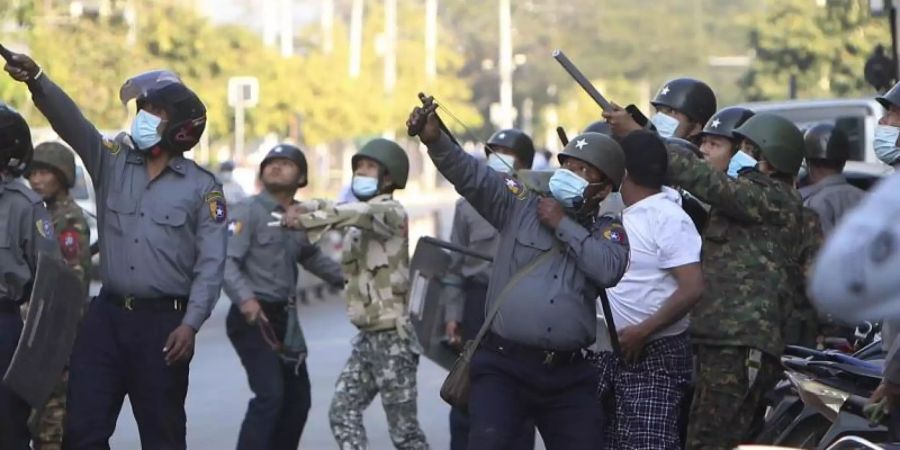 Ein Polizist schiesst in Mandalay mit einer Steinschleuder. Foto: Uncredited/AP/dpa