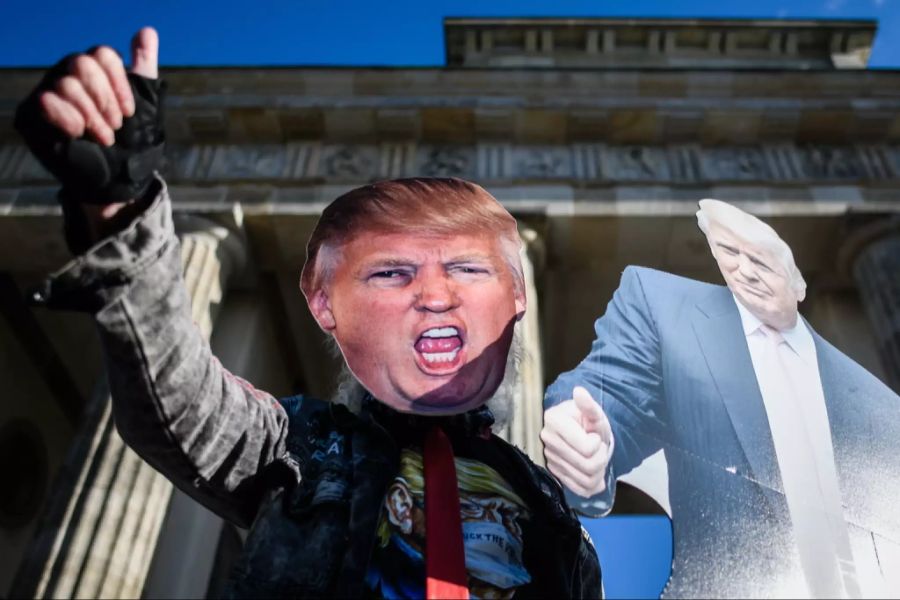 Eine Person mit Trump-Maske, Trump-Shirt und einem Trump-Plakat.