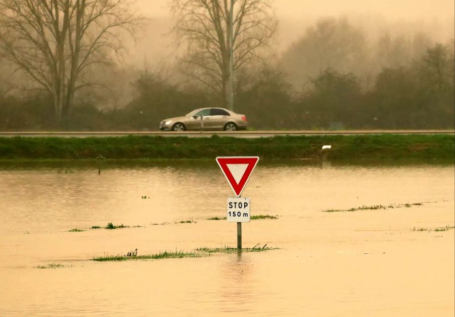 Ein Verkehrsschild ragt aus einer überfluteten Strasse heraus. Im ganzen Land sind die Strassen voll mit Wasser.