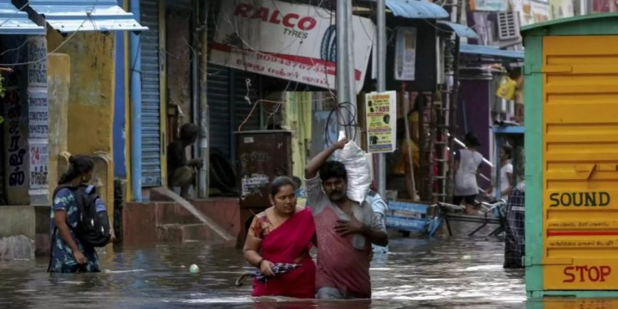 Menschen waten durch eine überflutete Strasse in Chennai. Sturm «Nivar» soll viel Regen bringen und Windgeschwindigkeiten bis 130 km/h erreichen. Foto: R. Parthibhan/AP/dpa