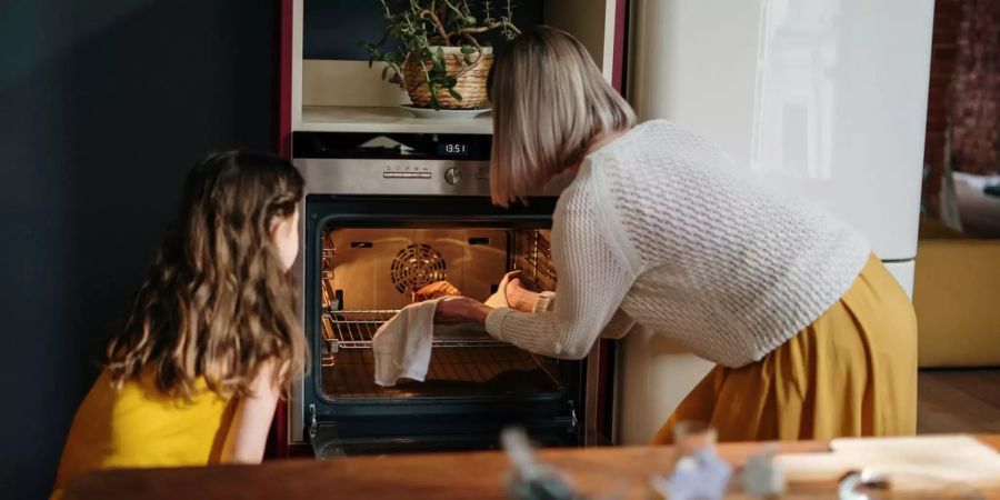 Frau schiebt etwas in Backofen