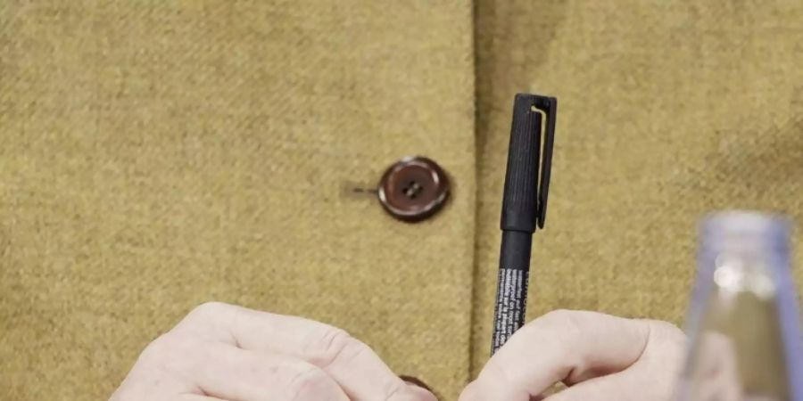 Angela Merkel hält einen Stift - nach den Beratungen mit den Länderchefs