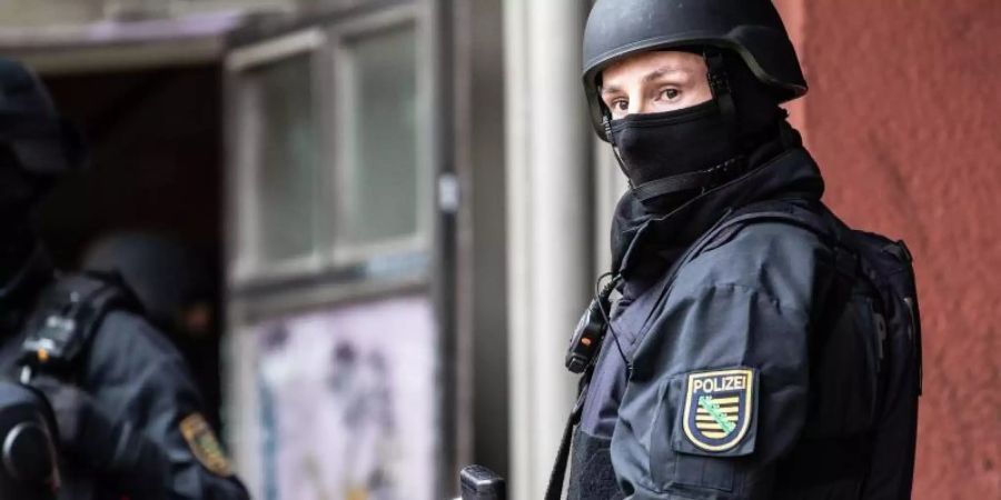 Ein bewaffneter Polizeibeamter im Eingang eines Wohnhauses in Berlin (Symbolbild). Foto: Paul Zinken/dpa