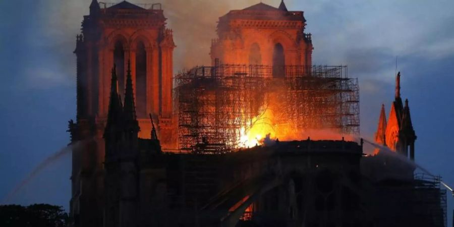 Ein Feuerwehrmann (r) versucht, das Feuer in der Kathedrale Notre-Dame zu löschen. Foto: Michael Euler/AP