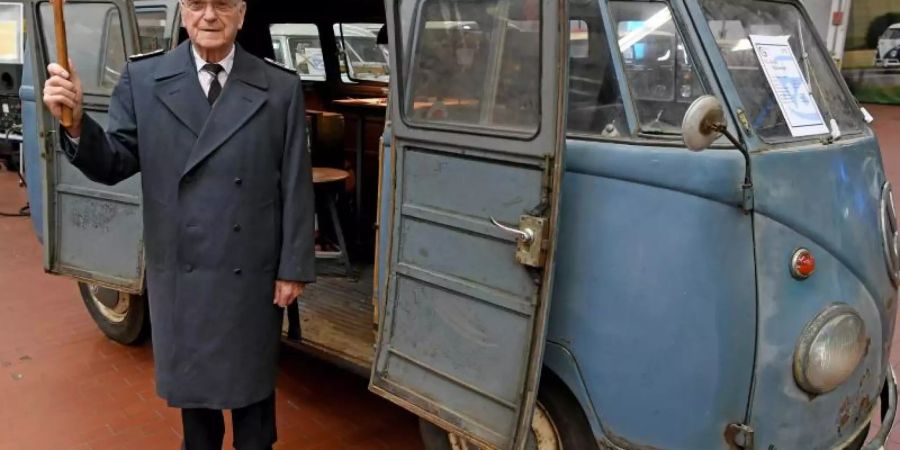 Heinz Scholze in historischer Uniform und mit Winkerkelle vor einem 66 Jahre alten T1 VW-Bulli in der Oldtimersammlung von VW-Nutzfahrzeuge. Foto: Holger Hollemann