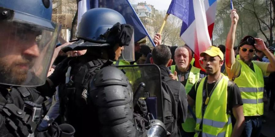 Polizisten vor Demonstranten und Anhängern der «Gelbwesten»-Bewegung, die an einer Protestkundgebung in Paris teilnehmen. Foto: Thibault Camus/AP