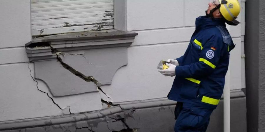 Ein Mitarbeiter des Technischen Hilfswerks steht in Wuppertal vor einem der Häuser, an dem ein breiter Riss sichtbar ist. Foto: Henning Kaiser