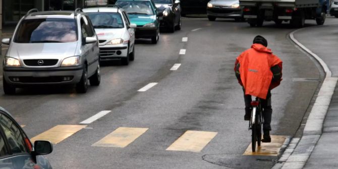 Velofahrer auf vielbefahrener Strasse