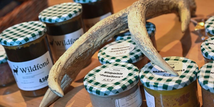 Wild-Fond und Wildpastete in Gläsern liegen im Wildladen neben einem Geweih.