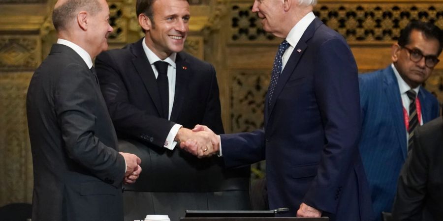 US-Präsident Joe Biden (r) und Frankreichs Präsident Emmanuel Macron begrüssen sich während des G20-Gipfels in Indonesien, daneben steht Bundeskanzler Olaf Scholz (SPD, l).