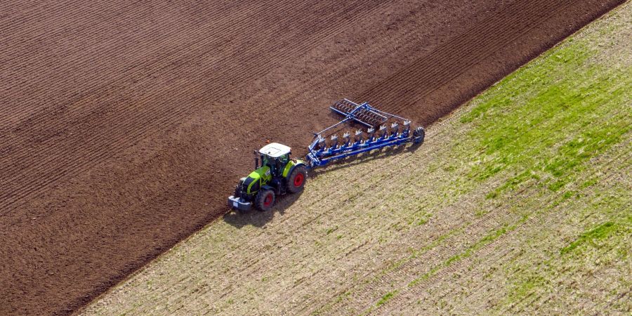 Ein Landwirt pflügt ein abgeerntetes Feld und bereitet es für die Neubestellung vor.