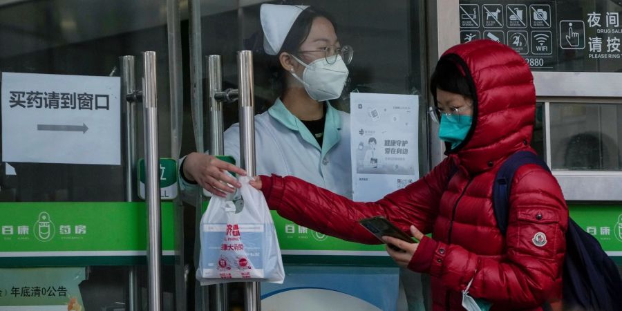 Eine Frau holt in einer Apotheke in Peking COVID-19-Antigen-Kits ab.