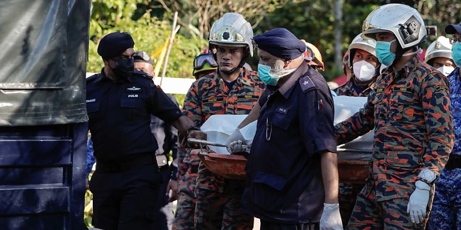 Rettungskräfte befördern gemeinsam eine Trage. Die Anzahl der Verstorbenen im Zusammenhang mit einem Erdrutsch auf einem Campingplatz ist auf 31 angestiegen, nachdem die letzte vermisste Person gefunden wurde. Foto: Amirul Azmi/BERNAMA/dpa