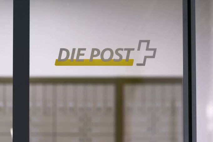 Das Logo der Schweizerischen Post auf der Eingangstür einer Filiale der Schweizerischen Post. Post