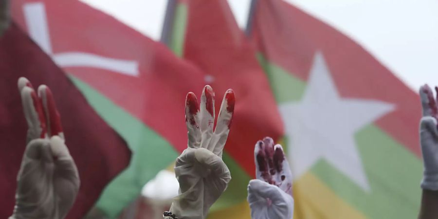 Myanmarische Demonstranten die in Taiwan leben, tragen rot bemalte Handschuhe und zeigen den symbolischen Drei-Finger-Gruss bei einem Protest gegen das Militärregime in Myanmar.(Symbolbild) Foto: Chiang Ying-Ying/AP/dpa