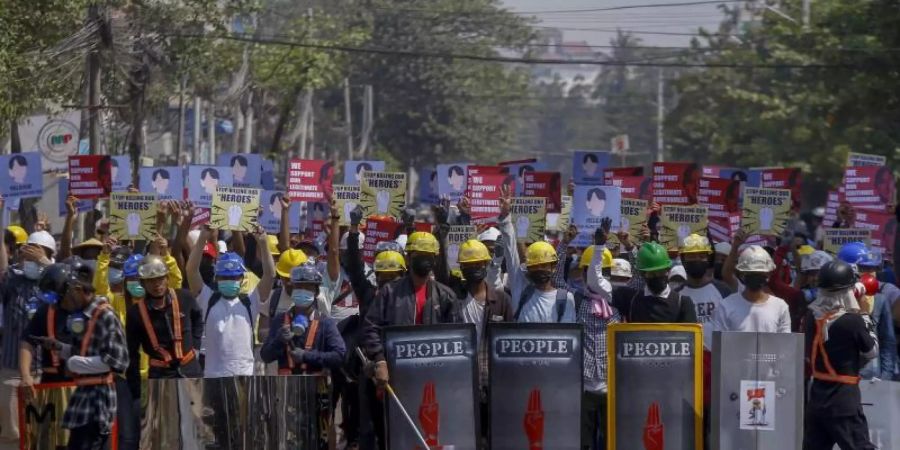 Anti-Coup-Demonstranten mit behelfsmässigen Schilden beziehen bei einem Protest in Yangon Stellung. Foto: Uncredited/AP/dpa