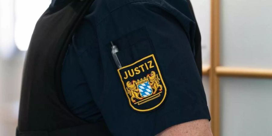 Ein Justizbeamter an der Eingangstür zum Gerichtssaal. Foto: Nicolas Armer/dpa