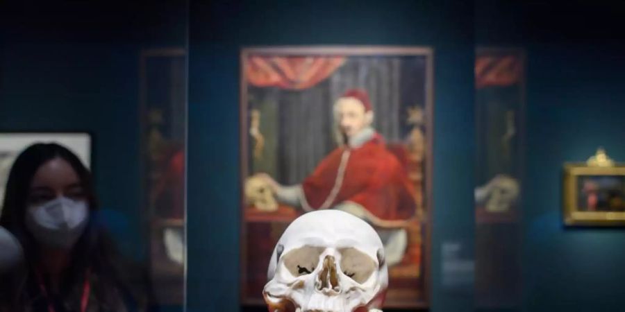 Der Totenkopf von Gian Lorenzo Bernini aus weissem Carrara-Marmor, im Hintergrund hängt das Porträt des Malers Guido Ubaldo Abbatini von Papst Alexander VII. mit Berninis Totenkopf. Foto: Robert Michael/dpa-Zentralbild/dpa