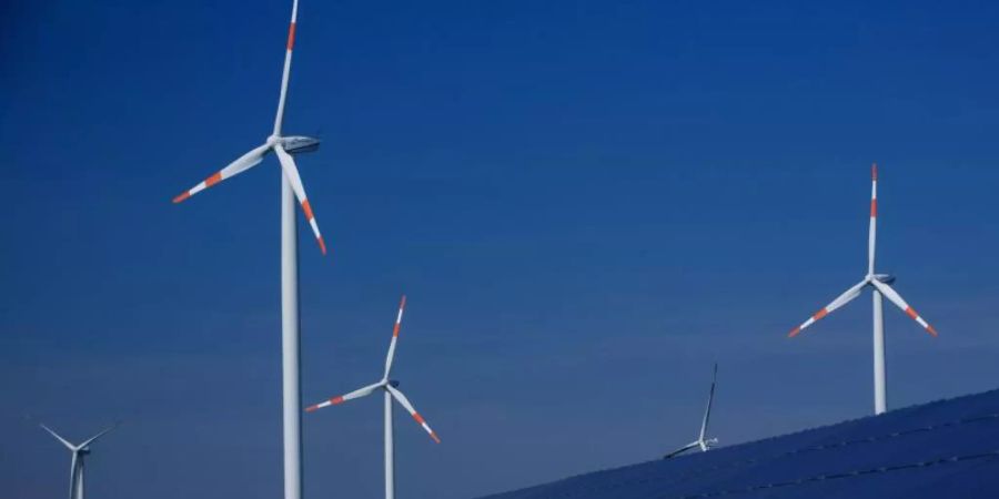 Windräder zur Stromerzeugung drehen sich in Mecklenburg-Vorpommern hinter einem Solarpark. Foto: Jens Büttner/dpa-Zentralbild/dpa