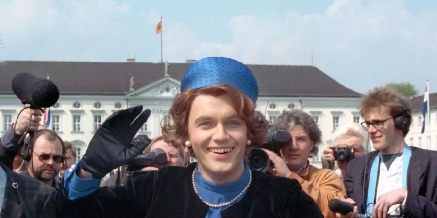 Verkleidet als Königin Beatrix der Niederlande winkt der Komiker Hape Kerkeling vor Schloss Bellevue für die Presse (1991). Foto: picture alliance / dpa