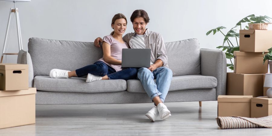 Junges Paar sitzt auf Couch mit Umzugskartons