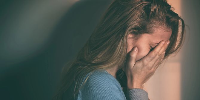 Traurige Frau hält sich die Hände vors Gesicht
