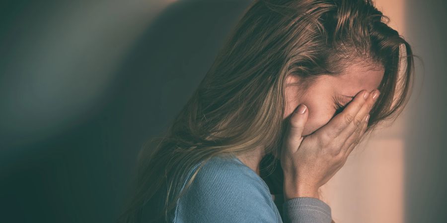 Traurige Frau hält sich die Hände vors Gesicht