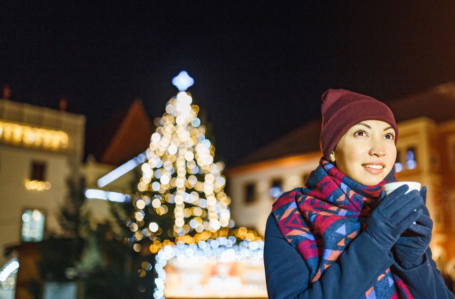 Frau mit Trinkbecher auf Weihnachtsmarkt