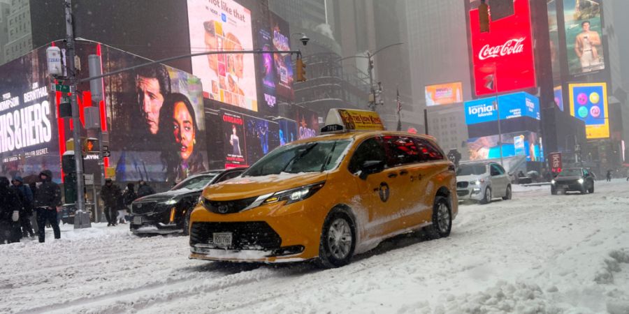 Fahrzeuge fahren über eine verschneite Straße am Times Square. Ein heftiger Wintersturm zieht derzeit mit klirrender Kälte, Schnee und Eis über große Teile der USA. Foto: Christina...
