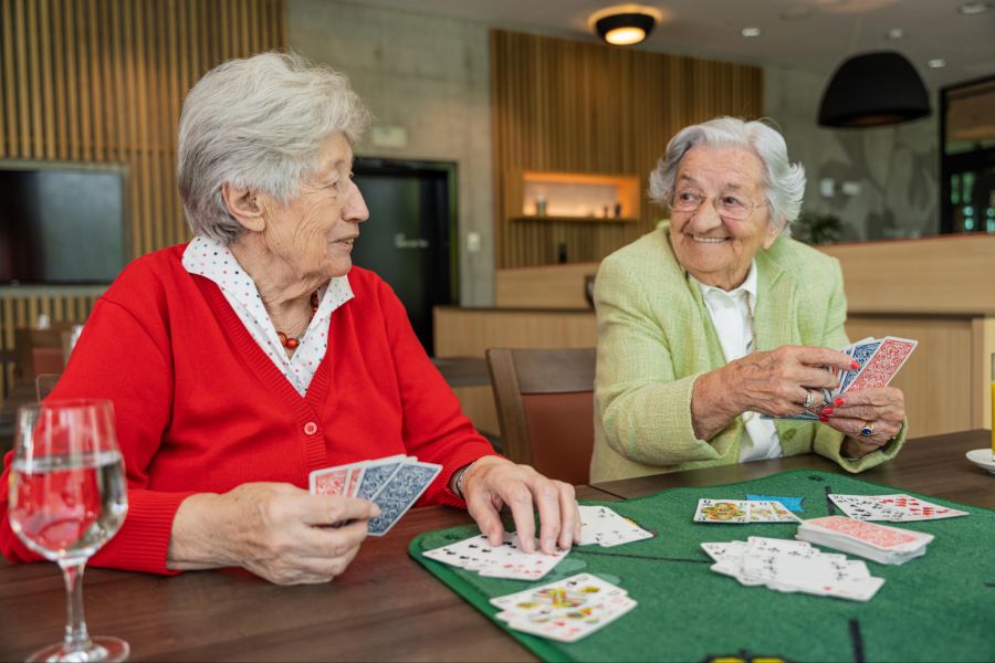 Betreutes Wohnen: Zwei ältere Frauen jassen zusammen.
