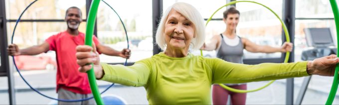 Hula-Hoop eignet sich für Menschen jeden Alters. Lächelnde grauhaarige Frau mit Hula-Hoop-Reifen