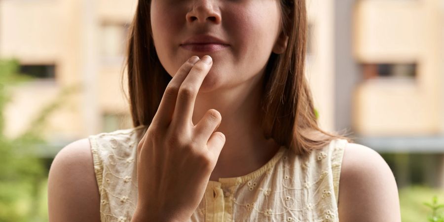 Frau tippt sich auf das Kinn. EFT-Tapping.