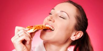 Frau isst genussvoll Stück Pizza