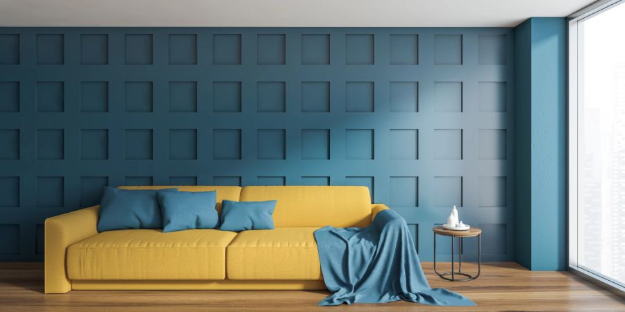 Gelbes Sofa mit blauer Wand, Kissen und Decke