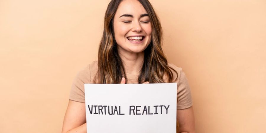 Frau hält lachend Schild hoch mit Aufschrift: virtual reality