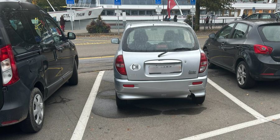 Beulen, ein Riss, Rost und eine kaputte Scheibe: Ein Mann sieht am Bahnhof Thun BE ein sichtlich mitgenommenes Auto.